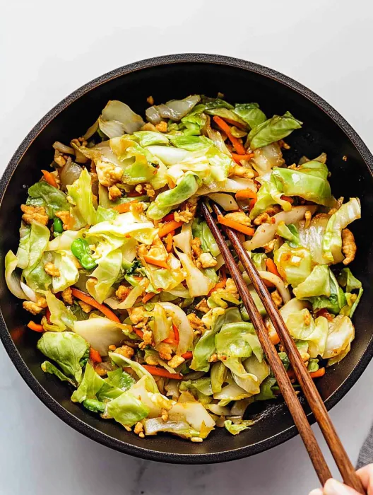 A bowl of vegetables with chopsticks.