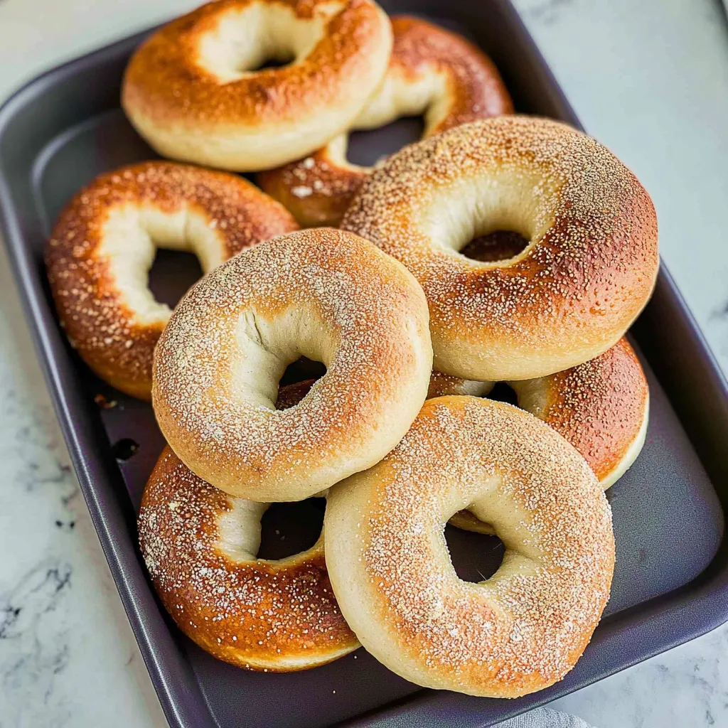 A tray of bagels with sesame seeds on top.