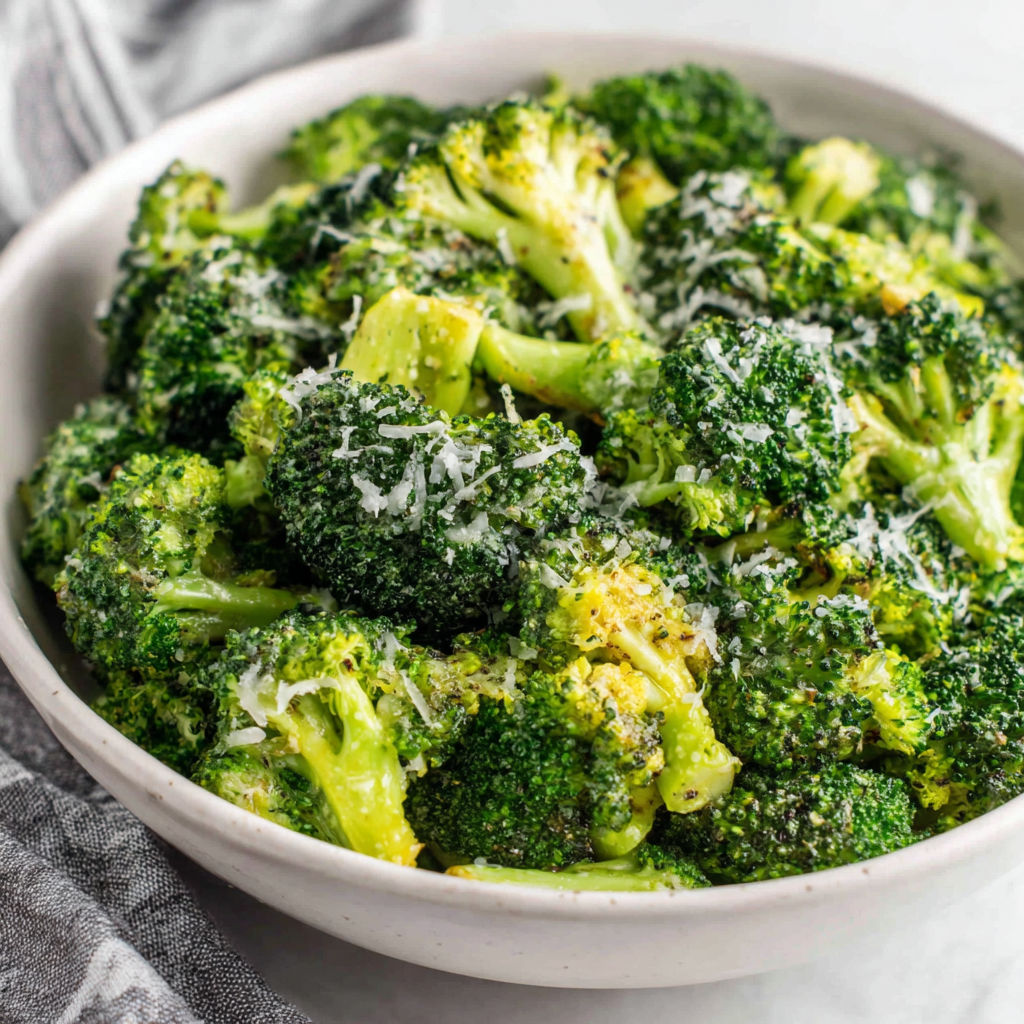 A bowl of broccoli with cheese on top.