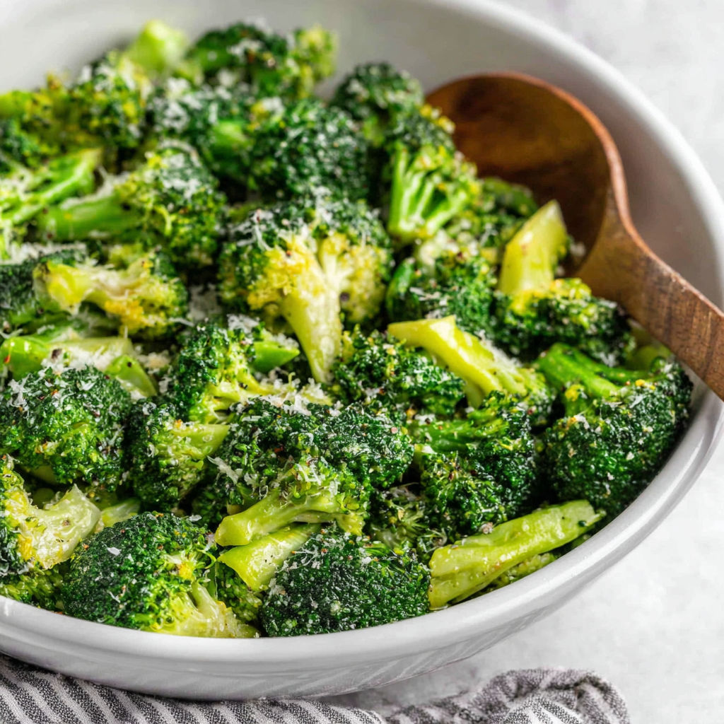 A bowl of broccoli with cheese on top.