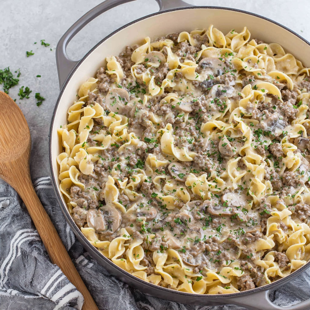 A bowl of pasta with mushrooms and meat.