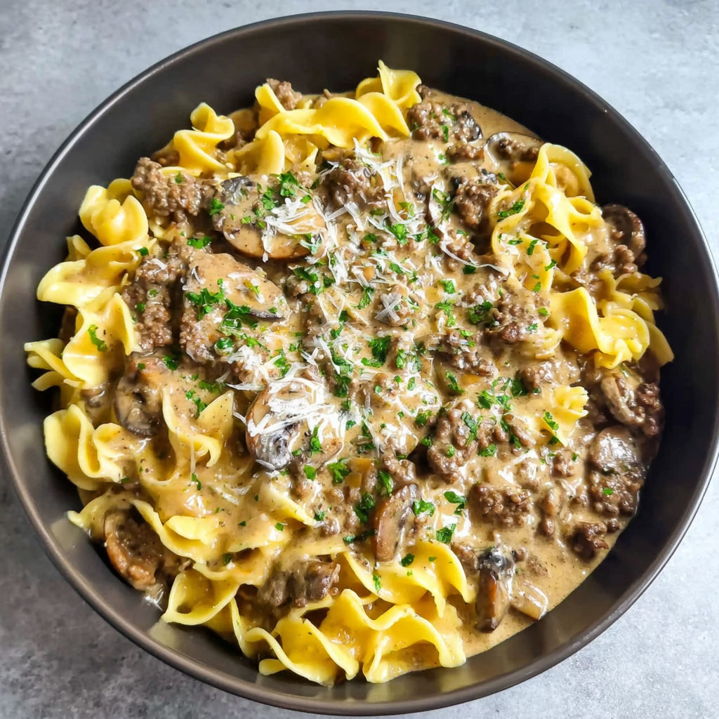 A bowl of pasta with mushrooms and meat.