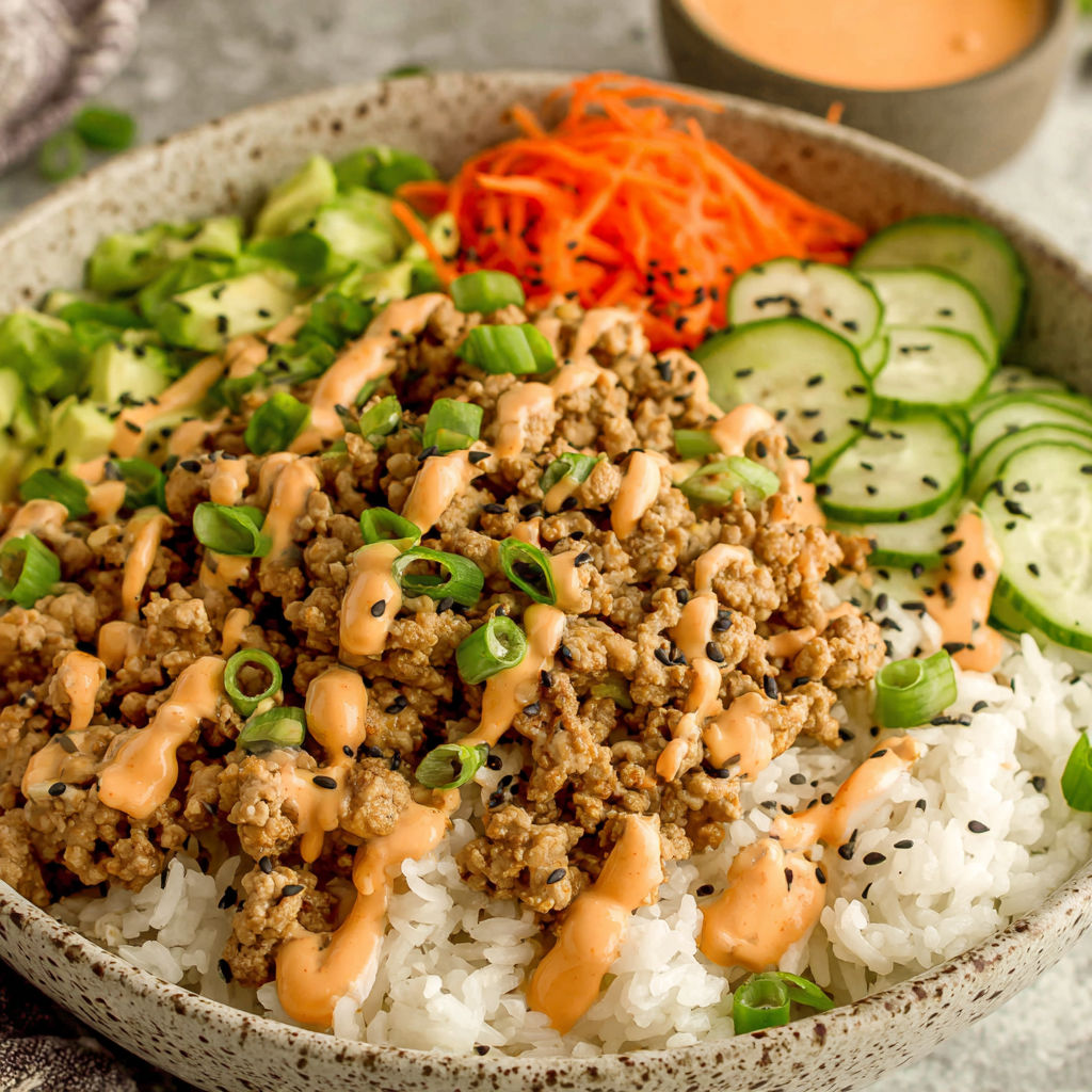 A bowl of ground turkey and rice with bang bang sauce.