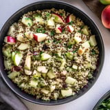 A bowl of food with apples, cucumbers, and rice.