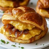 A sandwich with bacon and egg on a white plate.