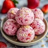 A bowl of pink balls with strawberries.