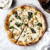 A pizza with chicken and spinach on top.