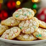 A plate of cookies with white icing and red and green sprinkles.