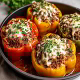 A bowl of stuffed peppers with cheese and meat.