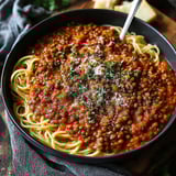 A bowl of lentil bolognese with spaghetti noodles.
