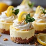 Three mini lemon cheesecakes with mint leaves on top.