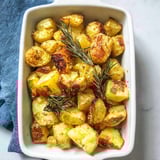 A white bowl filled with roasted potatoes and rosemary.