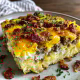 A slice of a breakfast casserole with bacon and cheese.