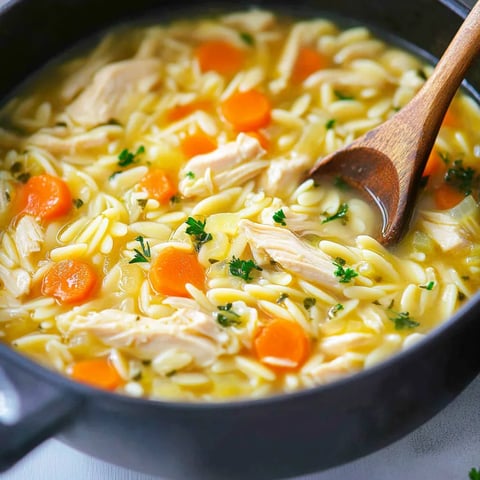 A bowl of soup with carrots and chicken.