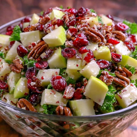 A bowl of fruit salad with apples, cranberries, and pecans.