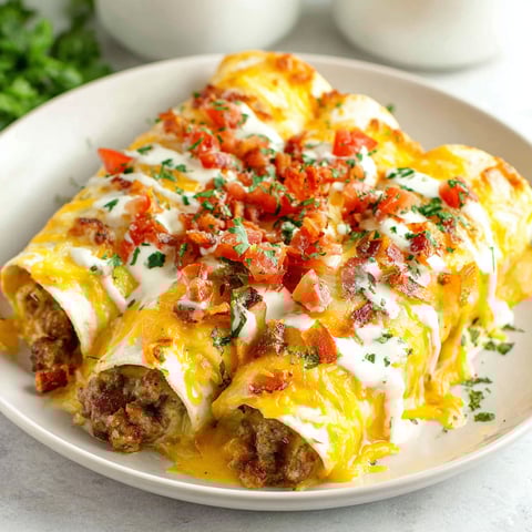 A plate of breakfast enchiladas with cheese and tomatoes.