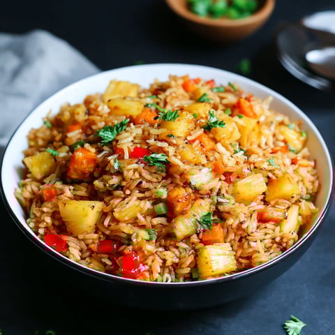 A bowl of rice with vegetables and pineapple.