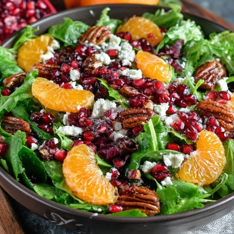 A bowl of salad with oranges, pomegranates, and walnuts.